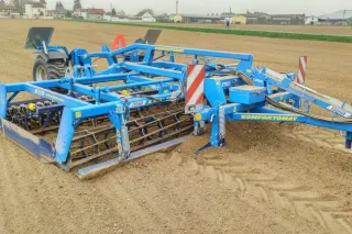 Modrý Kompaktomat Farmet K 450 za traktorem na poli