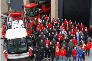 Skupina zaměstnanců před červenými postřikovači Agrifac