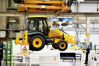 Žlutý stroj JCB ve výrobní hale