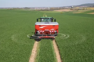 Traktor s rozmetadlem hnojiv Rauch Axis na zeleném poli