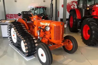 Zrenovovaný oranžový polopásový traktor Zetor 25A ve výstavní hale