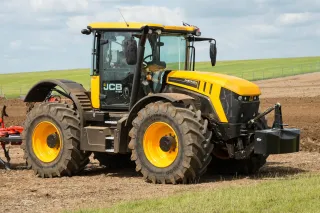 Žlutý traktor JCB Fastrac na poli