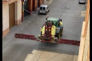 Traktor s postřikovačem dezinfikuje městskou ulici
