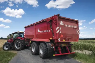 Traktor s červeným návěsem Annaburger na polní cestě