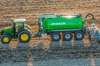 Zelený traktor s cisternou Joskin na poli