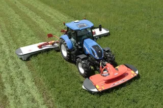 Modrý traktor se žacím strojem Kuhn na louce