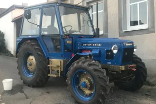 Renovovaný modrý traktor Zetor 6945 před domem
