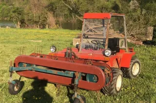 Červený svahový traktor Reform Metrac na louce