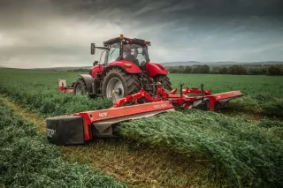 Červený traktor se žacím strojem SIP na poli