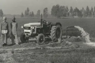 Historický černobílý snímek traktoru HMT s muži v Indii