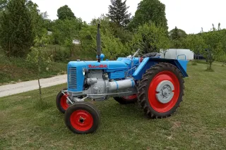 Renovovaný modrý traktor Zetor 25K u domu