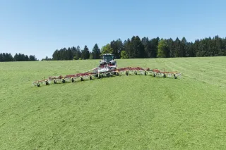 Traktor s dlouhým obracečem Pöttinger na louce