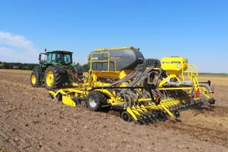 Zelený traktor táhne žlutý secí stroj Bednar Omega