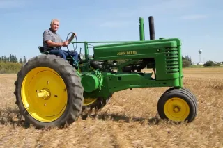 Muž řídí historický zelený traktor John Deere