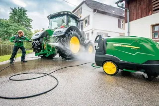 Muž myje tlakovou vodou velký traktor