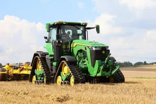 Zelený pásový traktor John Deere na poli