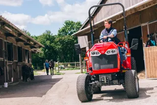 Kompaktní traktor Massey Ferguson u zemědělské budovy