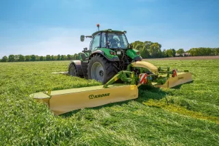 Traktor se žací kombinací Krone na louce