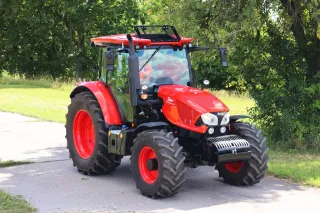 Červený traktor Zetor na cestě u stromů