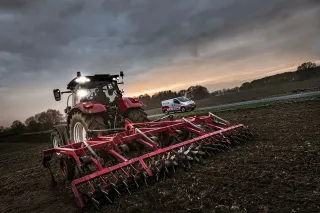Traktor s rozsvícenými pracovními LED světly za soumraku