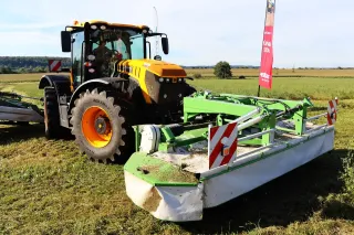 Žlutý traktor JCB Fastrac se žacím strojem na louce