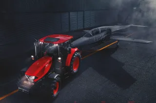 Červený traktor Zetor před tmavou budovou