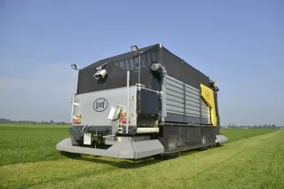 Autonomní krmný vůz Lely Exos u zemědělské budovy