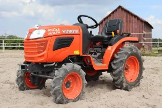 Detail oranžového traktoru Kubota B1220 u jízdárny