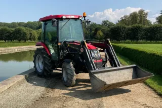 Červený malotraktor TYM u vodní nádrže
