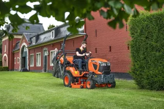 Travní traktor Kubota G u historické budovy