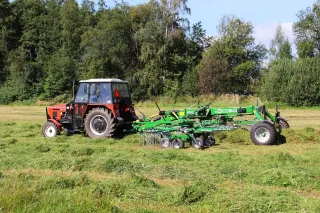 Traktor s rotorovým shrnovačem McHale na louce