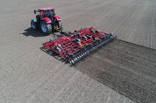 Traktor táhne kultivátor Kverneland Tiger po poli