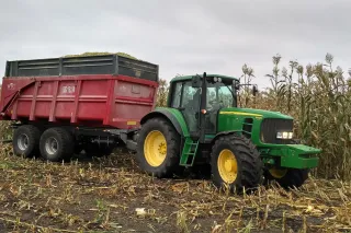 Traktor John Deere s návěsem při sklizni kukuřice