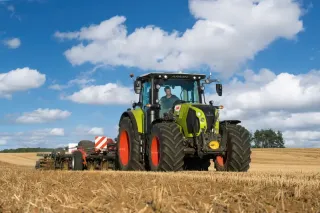 Traktor Claas Arion na poli pod modrou oblohou