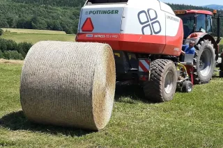 Kulatý balík obalený sítí u lisu Pöttinger