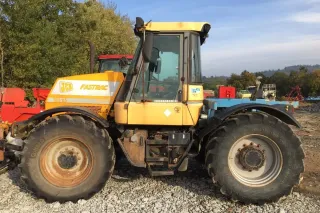 Žlutý traktor JCB Fastrac u stroje na farmě
