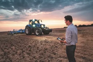Modrý traktor New Holland při práci za soumraku