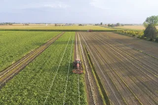 Letecký pohled na zemědělský stroj pracující v pásových řádcích pole