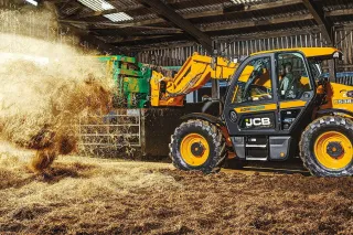 Teleskopický manipulátor JCB Loadall přemísťuje seno ve stodole