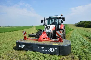 Traktor s čelním žacím strojem SIP Silvercut Disc na louce