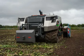 Šedý autonomní pásový robot AgXeed na poli