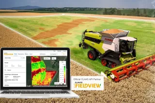 Sklízecí mlátička Claas na poli a notebook s mapou výnosů Climate FieldView