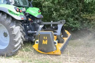 Žlutý mulčovač Müthing za zeleným traktorem u porostu