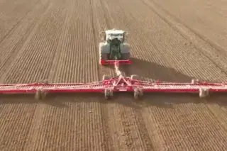 Traktor s širokými červenými prutovými bránami Horsch Cura ST na poli