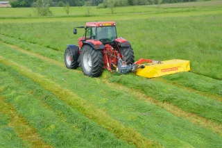 Traktor se žlutým žacím strojem Rožmitál při sečení louky