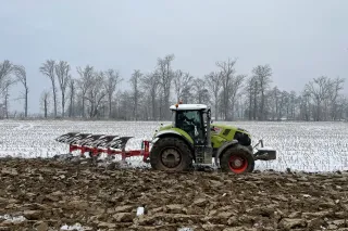 Traktor Claas s pluhem Sukov MaxGreen při orbě zasněženého pole