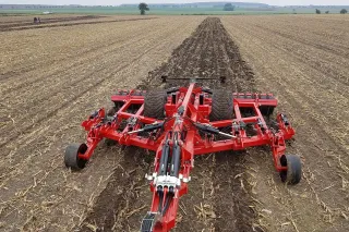 Červený podrývák SUMO Subsoiler při práci na poli