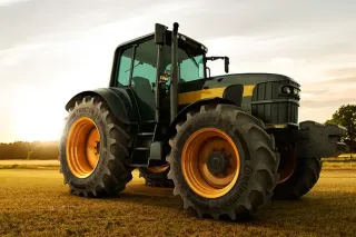 Tmavý traktor s pneumatikami Continental na poli při západu slunce