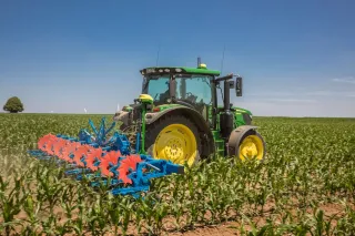 Traktor John Deere s navigačním systémem při práci na poli