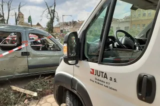 Dodávka firmy JUTA vedle poničeného auta v obci zasažené tornádem